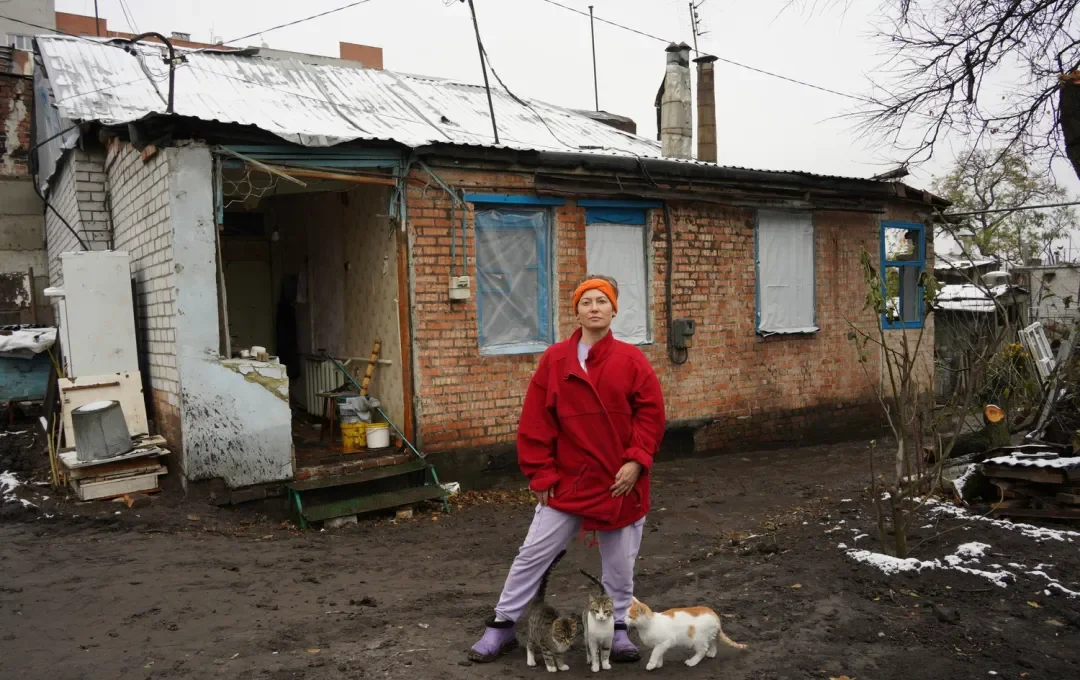 Ukrainian lady in front of bombed home