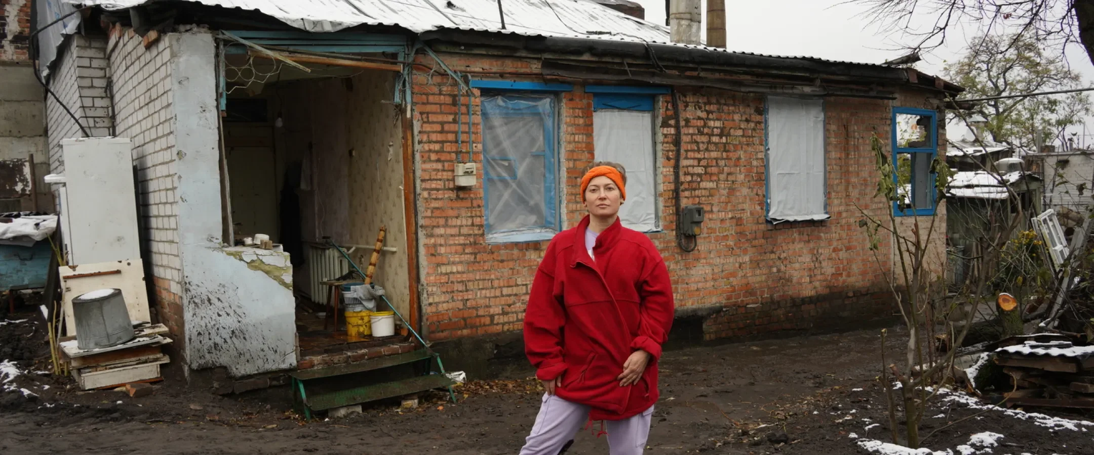 Ukrainian lady in front of bombed home